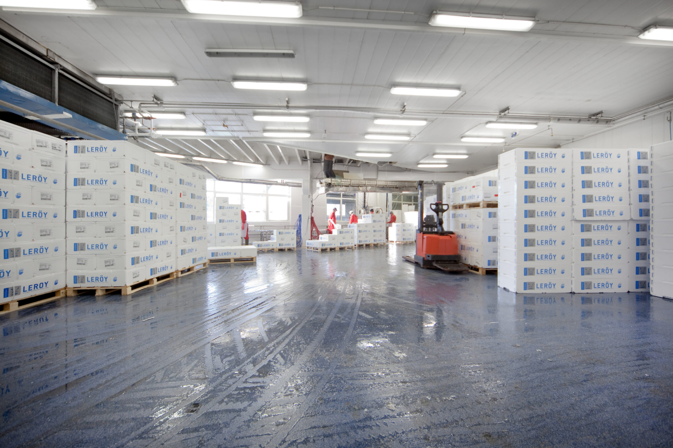 Blue seamless acrylic floor in a seafood industry warehouse with pallets of polystyrene boxes and a red forklift