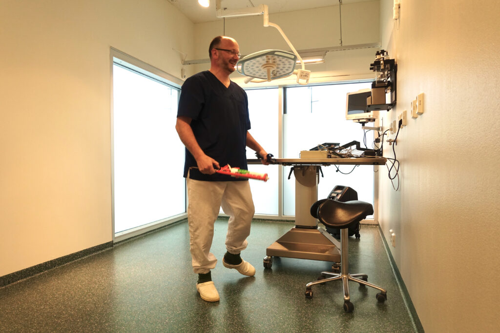 Staff member wheeling an equipment trolley across the green acrylic floor in the clinic's operating theatre