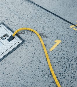 Yellow cable from an electrical floor hatch in grey industrial flooring with yellow number markings