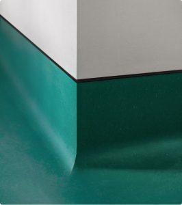 Green seamless acrylic coating with coving running smoothly up a white wall corner