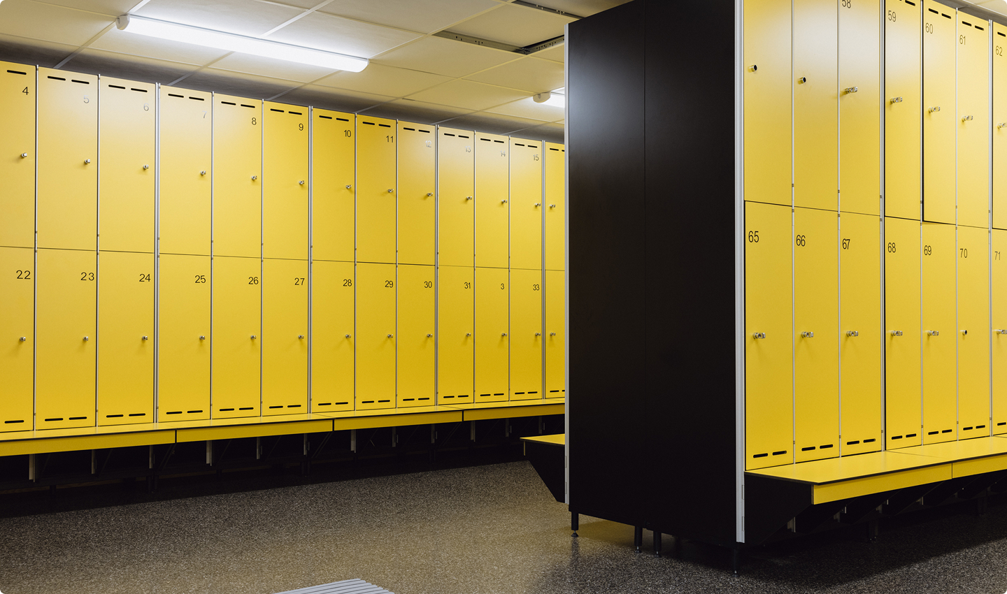 Locker room with yellow lockers and dark speckled industrial flooring